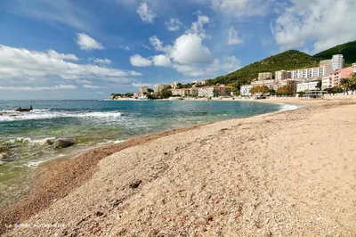 a sandy beach with buildings and the ocean at Trottel a Livia in Ajaccio