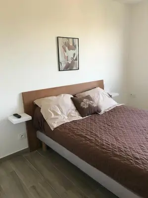 a bed in a white room with avertisement at Appartement F4 pour 6 personnes in Ajaccio