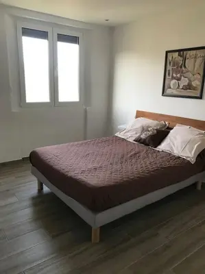 a bed in a bedroom with two windows at Appartement F4 pour 6 personnes in Ajaccio