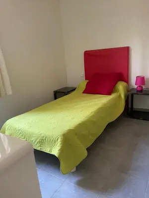 a bedroom with a yellow bed with a red headboard at Maison T4 Saint Cyprien in Lecci
