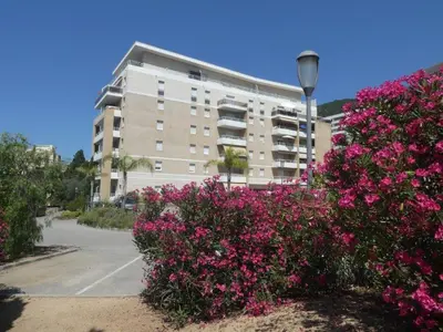 a large building with pink flowers in front of it at Ajaccio Sanguinaires T2 150métres de la mer in Ajaccio