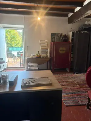 a living room with a table and a kitchen with a window at Maison de village in Zevaco
