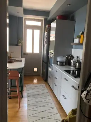 a kitchen with white cabinets and a table and a door at T4 Pieds dans l'eau ! in Ajaccio