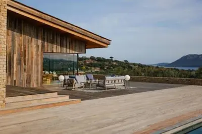 a house with a deck with chairs and a pool at Villa Wooden Horizon - Mer Montagne 18 pers in Porto-Vecchio