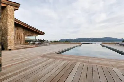 a wooden deck next to a body of water at Villa Wooden Horizon - Mer Montagne 18 pers in Porto-Vecchio