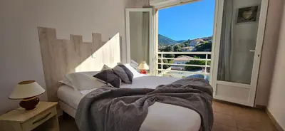 a bedroom with a bed and a large window at Beau T3 Central - Vue mer & Piscine - A Funtana in Propriano