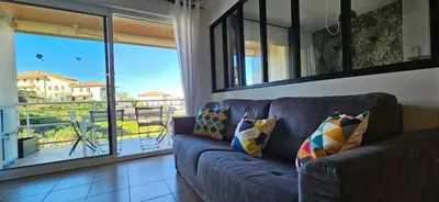 a blue couch in a living room with a balcony at Beau T3 Central - Vue mer & Piscine - A Funtana in Propriano