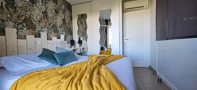 a bedroom with a bed with a yellow blanket on it at Beau T3 Central - Vue mer & Piscine - A Funtana in Propriano