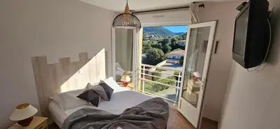 a bedroom with a bed and a large window at Beau T3 Central - Vue mer & Piscine - A Funtana in Propriano