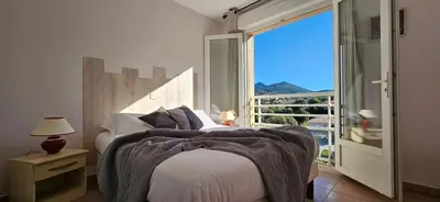 a bedroom with a bed and a large window at Beau T3 Central - Vue mer & Piscine - A Funtana in Propriano