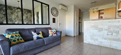 a living room with a couch and a clock on the wall at Beau T3 Central - Vue mer & Piscine - A Funtana in Propriano
