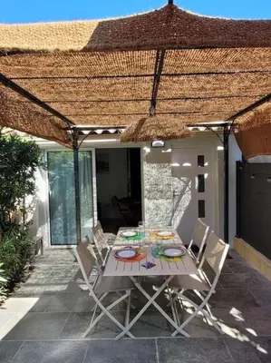 a table and chairs on a patio with a roof at Maison au bord de la mer in Poggio-Mezzana