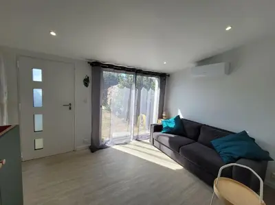 a living room with a black couch and a large window at Maison au bord de la mer in Poggio-Mezzana
