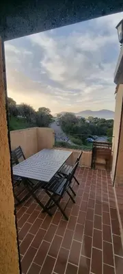 a table and chairs on a balcony with a view of a river at Appartement accès piscine collective Porticcio Corse du sud in Porticcio