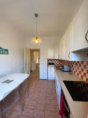 a kitchen with a table and a white refrigerator at appartement Cyrnos 3Pc 73m2 in Ajaccio