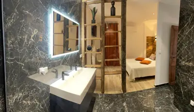 a bathroom with a sink and a mirror and a bed at appartement de standing avec jacuzzi exterieur in Zonza
