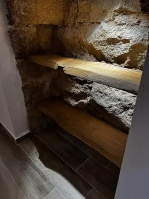 a stone wall with a wooden bench in a room at appartement de standing avec jacuzzi exterieur in Zonza