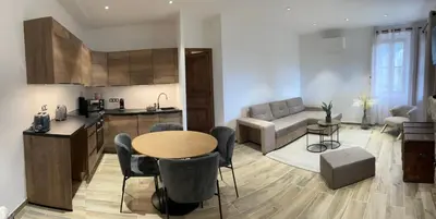 a kitchen and living room with a table and chairs at appartement de standing avec jacuzzi exterieur in Zonza
