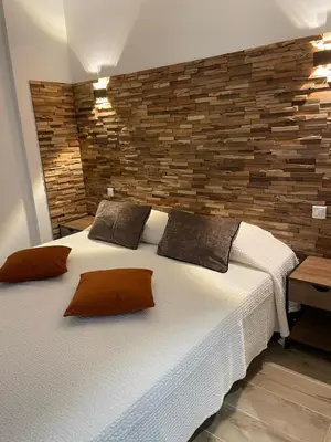 a bedroom with two beds and a brick wall at appartement de standing avec jacuzzi exterieur in Zonza