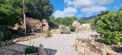 a garden with a bench and a stone building at Cottage bergerie en pierres avec jacuzzi en corse 6 personnes, 3 chambres in Coti-Chiavari