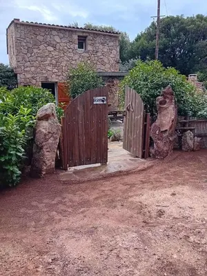 an entrance to a stone house with a wooden gate at Cottage bergerie en pierres avec jacuzzi en corse 6 personnes, 3 chambres in Coti-Chiavari