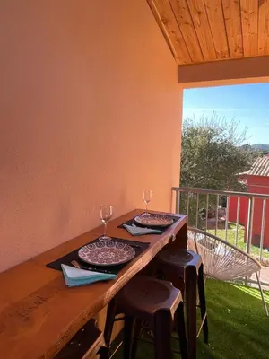 a wooden table with two plates and glasses on it at Appartement CERICA proche de la plage de Saint Cyprien in Lecci