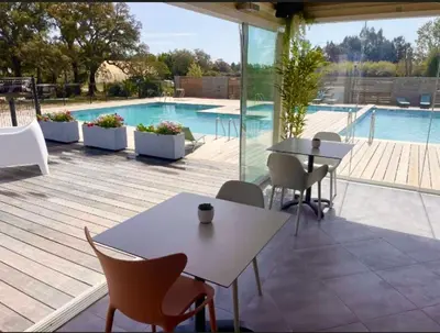 a patio with tables and chairs and a swimming pool at Appartement CERICA proche de la plage de Saint Cyprien in Lecci