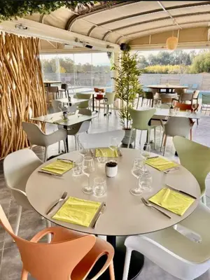 a table and chairs in a restaurant with a view at Appartement CERICA proche de la plage de Saint Cyprien in Lecci