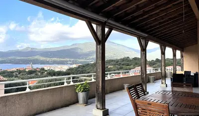 a balcony with chairs and a view of the mountains at Appartement avec vue imprenable sur la mer, terrasse et piscine in Propriano