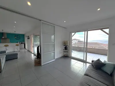 a living room with a couch and a kitchen at Appartement avec vue imprenable sur la mer, terrasse et piscine in Propriano