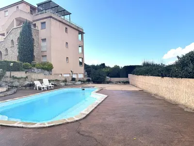 a swimming pool in front of a building at Appartement avec vue imprenable sur la mer, terrasse et piscine in Propriano