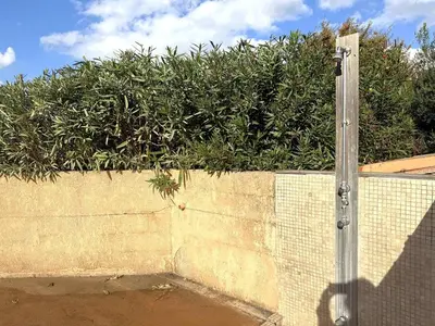 a concrete wall with a hedge in front at Appartement avec vue imprenable sur la mer, terrasse et piscine in Propriano