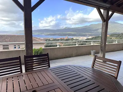 a patio with a table and chairs on a balcony at Appartement avec vue imprenable sur la mer, terrasse et piscine in Propriano
