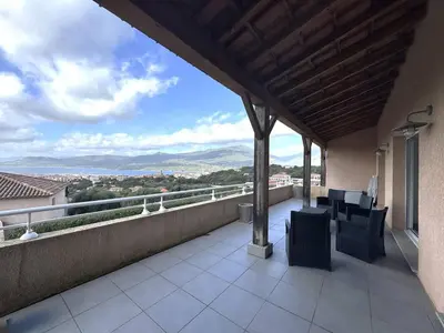 a balcony with chairs and a view of the mountains at Appartement avec vue imprenable sur la mer, terrasse et piscine in Propriano