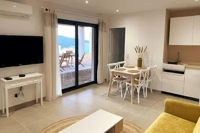 a living room with a kitchen and a table with chairs at Rez de villa Favone in Conca