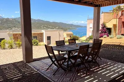 a table and chairs on a patio with a view of the ocean at Rez de villa Favone in Conca
