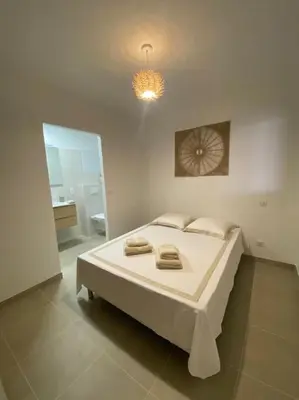 a white bedroom with a bed and a mirror at Rez de villa Favone in Conca