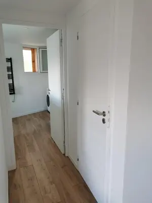 an empty room with a white door and wooden floors at Appartement neuf dans hameau proche porto vecchio in Porto-Vecchio