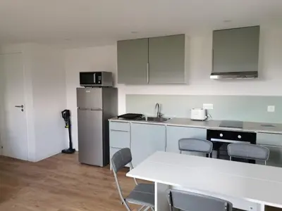 a kitchen with white cabinets and a white table and chairs at Appartement neuf dans hameau proche porto vecchio in Porto-Vecchio