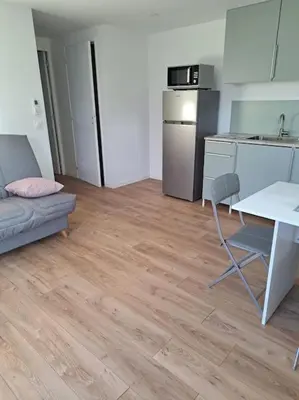 a kitchen with a couch and a table and a refrigerator at Appartement neuf dans hameau proche porto vecchio in Porto-Vecchio