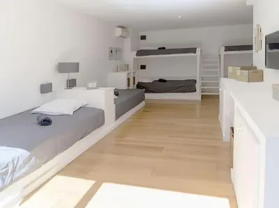 a white bedroom with a large bed and a wooden floor at Villa Palombaggia in Porto-Vecchio