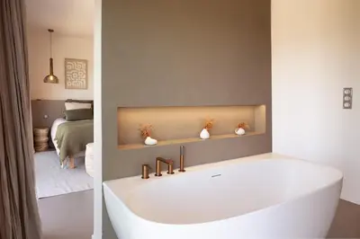 a bathroom with a white tub and a bedroom at Villa Yaya in Cervione