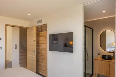 a bedroom with a television on a white wall at Villa Yaya in Cervione