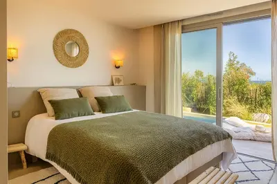 a bedroom with a large bed and a large window at Villa Yaya in Cervione