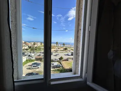 a window with a view of a parking lot at Appartement de charme vue mer in Kamiesch
