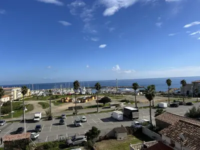 a parking lot with cars and the ocean in the background at Appartement de charme vue mer in Kamiesch
