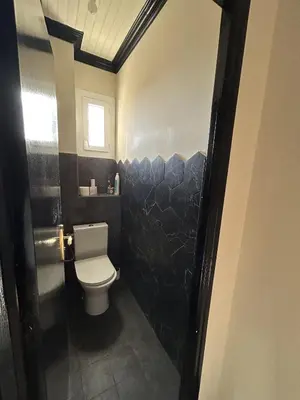 a bathroom with a toilet and a black wall at Appartement de charme vue mer in Kamiesch