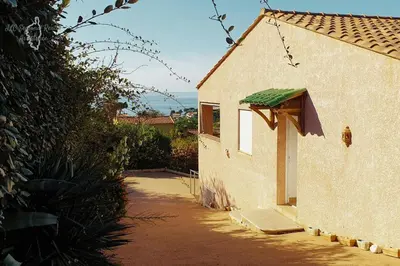a building with a green roof next to a street at A Casa Apa Vue mer Plage a pied Ruppione Pietrosella in Pietrosella