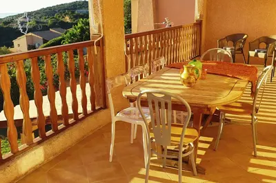 a wooden table and chairs on a balcony at A Casa Apa Vue mer Plage a pied Ruppione Pietrosella in Pietrosella