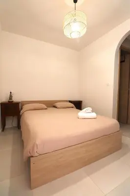a bedroom with a large bed with a chandelier at LE FINOSELLO - T2 Cosy sur Ajaccio avec Clim, Wifi & Parking - proche Port & Aéroport in Ajaccio